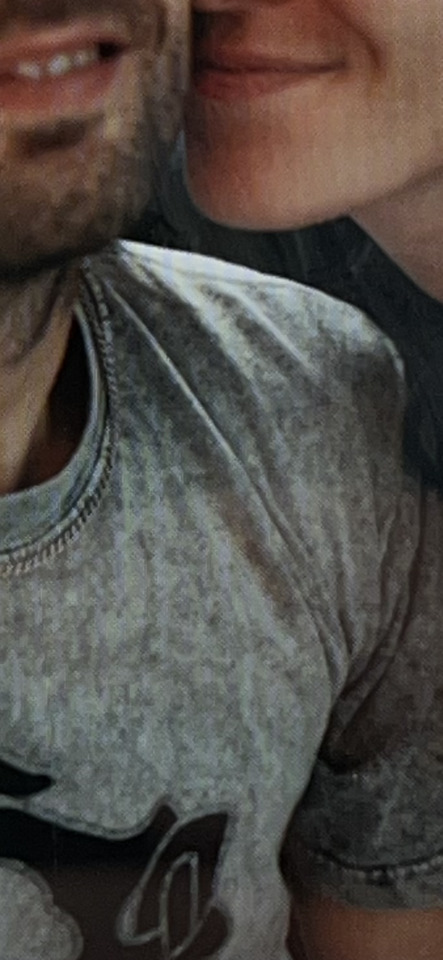 Close-up of two people's lower faces, one bearded, sharing an intimate moment, possibly a kiss.