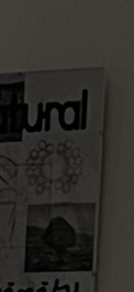 A dark, close-up shot of a poster with partial text "tural", abstract patterns, and a landscape image.