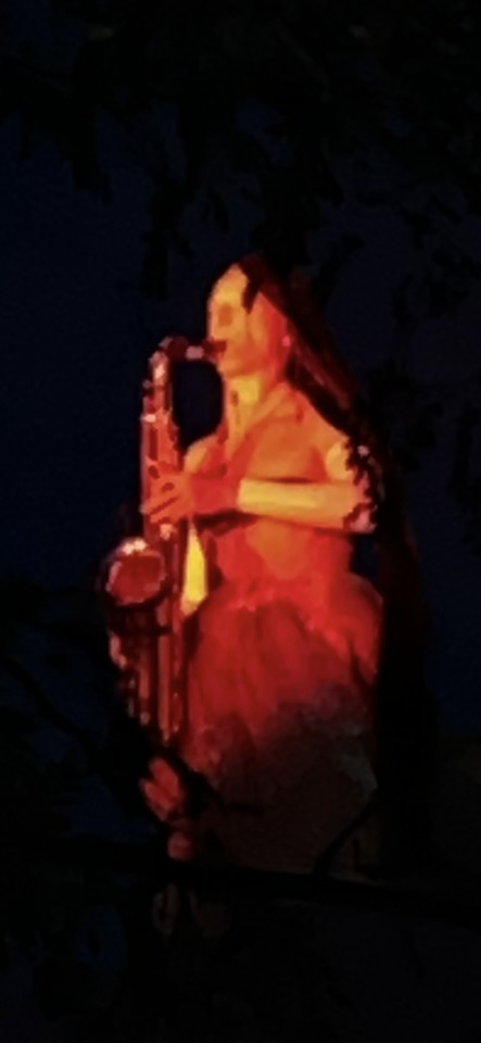 A musician, dramatically lit in red and orange, passionately plays a saxophone against a dark background.