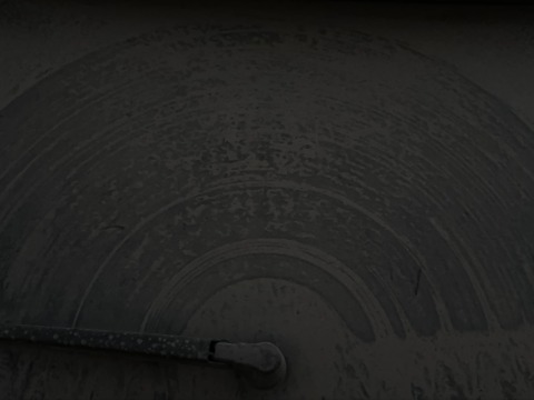 A dark, dusty car windshield with visible arcs from a wiper blade and a wiper arm at the bottom.